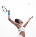 Young tennis player throwing a ball into the air. Fit athlete waiting to hit a ball during a tennis match. African Royalty Free Stock Photo