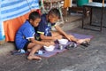 Young Thai boys sitting and eating at street