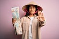 Young thai tourist woman on vacation wearing traditional conical asian hat holding city map with open hand doing stop sign with Royalty Free Stock Photo