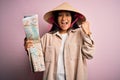 Young thai tourist woman on vacation wearing traditional conical asian hat holding city map screaming proud and celebrating Royalty Free Stock Photo