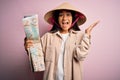 Young thai tourist woman on vacation wearing traditional conical asian hat holding city map very happy and excited, winner Royalty Free Stock Photo