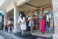 a young thai woman praying at buddah temple with Corona mask. In the background: dance and music group in traditional clothes