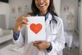 Young therapist doctor woman showing greeting card with red heart Royalty Free Stock Photo