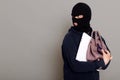 A young thief male dressed in a black hoodie with a disguised face runs away after stealing with other people`s belongings, bag,
