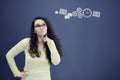 Young thinkful woman on blue gray background with finance graphs.