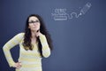 Young thinkful woman on blue gray background with finance graphs.