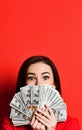 Young thinking pretty woman hiding behind bunch of money banknotes Royalty Free Stock Photo