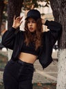 Young thinking teen hipster woman looking near the tree  on the street background in black style clothing and cool cap. Autumn Royalty Free Stock Photo