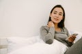 Young asian girl with phone sitting on the bed