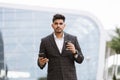 Young thoughtful Arab man standing outside modern building and drinking take away coffee Royalty Free Stock Photo