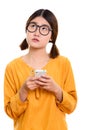 Young thoughtful Asian woman holding mobile phone Royalty Free Stock Photo