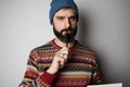 Young thoughtful bearded man in blue beanie thinking about test over empty background.