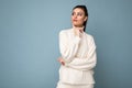 Young thoughtful brunette woman with wearing white casual sweater isolated over blue background looking confident at the Royalty Free Stock Photo