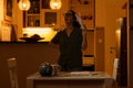 Young thoughtful Caucasian woman with glasses holds documents while standing in kitchen. Concept of overdue taxes