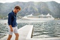 A young thoughtful guy is walking on the dock on the seaside. Holiday, sea