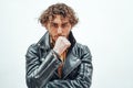 Young and and thoughtful male model with curly hair posing in a studio wearing leather jacket Royalty Free Stock Photo