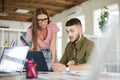 Young thoughtful man in shirt and upset woman in striped T-shirt and eyeglasses working together with laptop. Business