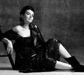 Portrait of young beautiful dreamy pregnant woman in black lace dress and leather jacket sitting on floor and looking up Royalty Free Stock Photo