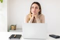 Young thoughtful pretty woman with laptop sitting at desk looking away Royalty Free Stock Photo