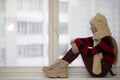 A young thoughtful teenager girl sits at home on the windowsill and looks