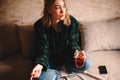 Young thoughtful woman holding cup of tea and chocolate while sitting on sofa Royalty Free Stock Photo