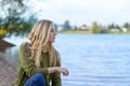 Young thoughtful woman sitting by lake Royalty Free Stock Photo