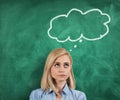 Young thoughtful woman standing on green blackboard