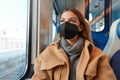 Young thoughtful woman wearing black medical face mask on train looking through the window. Concept of travelling and using public Royalty Free Stock Photo