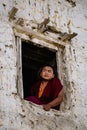 Young Tibetan Buddhist Monk sitting by the window of old building and looking out, Nepal