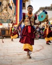 Young Tibetan Buddhist in traditional outfit Dancing holding a Damaru at the Tiji Festival in Nepal
