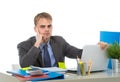 Young tired businessman overworked and upset looking worried sitting at computer desk