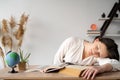 Young tired depressed college student sleeping on the table with textbooks or books. The girl was preparing for the exam Royalty Free Stock Photo