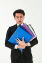 A young tired employee holding a stack of heavy folders, looking unhappy on his face and suffering from overloaded work, on white