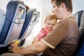 Young tired father and his crying baby daughter during flight on airplane going on vacations