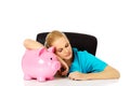 Young tired female doctor or nurse sitting behind the desk and holding a piggybank Royalty Free Stock Photo