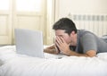 Young tired man lying on bed or couch working on computer laptop at home wireless connected to internet in technology concept Royalty Free Stock Photo