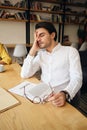 Young tired man sitting at the table with notepad leaning head on hand sleeping at work in modern office Royalty Free Stock Photo