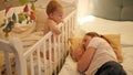Young tired mother fell asleep next to her baby crying in bed. Concept of parenting, parent fatigue and children Royalty Free Stock Photo