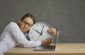 Employee freelancer sleeping at work hugging clock at desk front of laptop Royalty Free Stock Photo