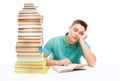 Young tired student sitting at the desk with high books stack Royalty Free Stock Photo