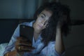 Young tired and thoughtful hipster woman on bed late at night using social media app on mobile phone online dating in online Royalty Free Stock Photo