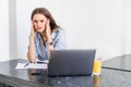 Young tired woman sitting in front of laptop while touching her forehead during work over project Royalty Free Stock Photo