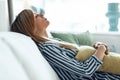 Young tired woman relaxing on couch with pillow for stomachache in living room at home Royalty Free Stock Photo