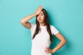 Young tired woman in white t-shirt, sighing and making facepalm to express annoyance, feeling fed up and tensed