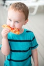 Young toddler boy on patio deck outside at sunset down at shore eating pizza