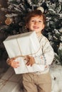 Young toddler Caucasian Boy Holding Christmas Present In Front Of Christmas Tree. Cute happy smiling boy. Vertical photo Royalty Free Stock Photo