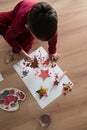 Young toddler making Christmas decorations kneeling on the floor