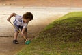 Young boy sweeping leaves from the driveway