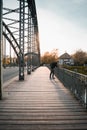 Young tourist with a backpack walking alone on a wooden bridge during the sunset Royalty Free Stock Photo