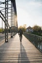 Young tourist with a backpack walking alone on a wooden bridge during the sunset Royalty Free Stock Photo